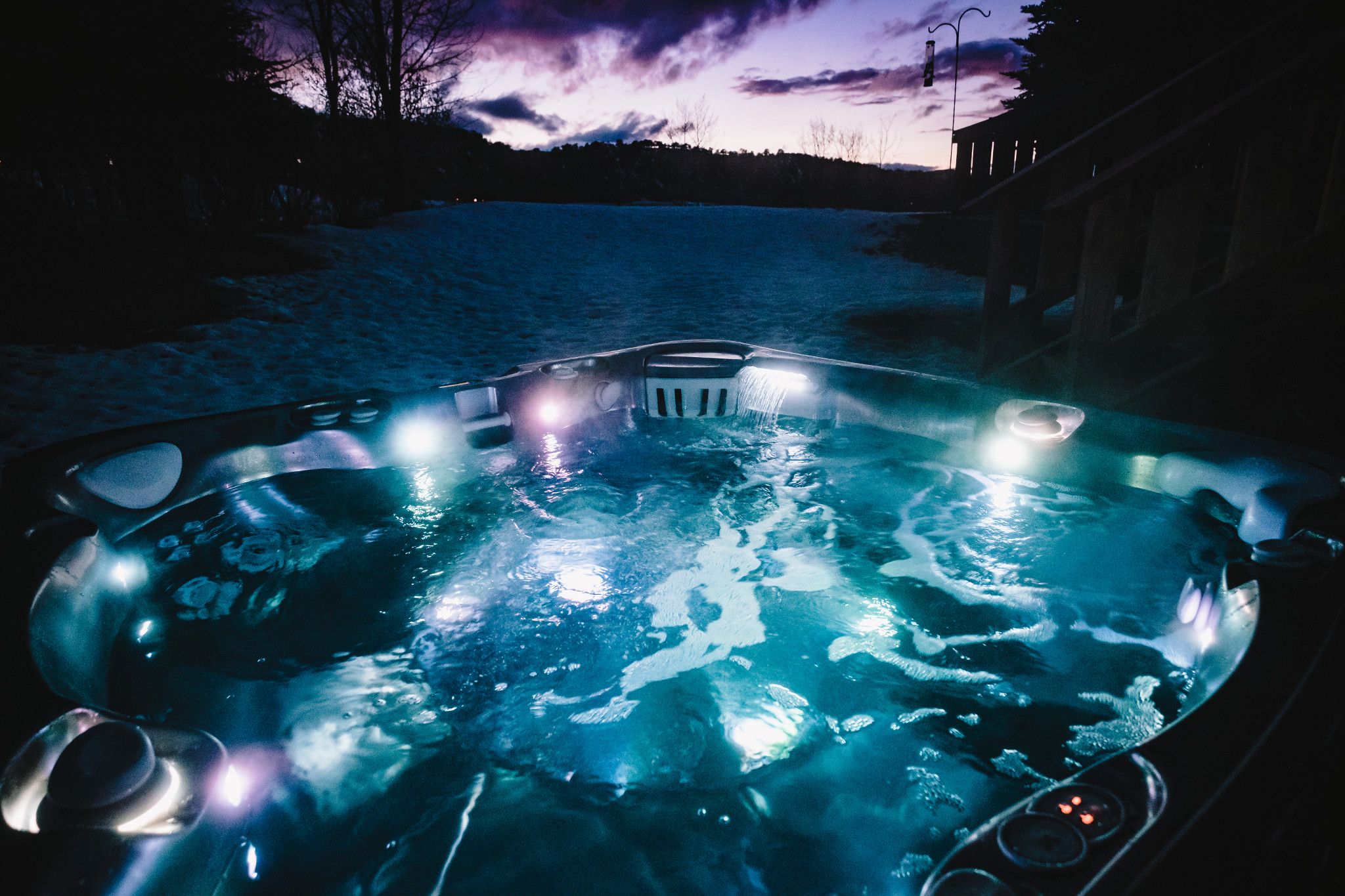 Caldera spa met blauwe verlichting en waterval bij zonsondergang
