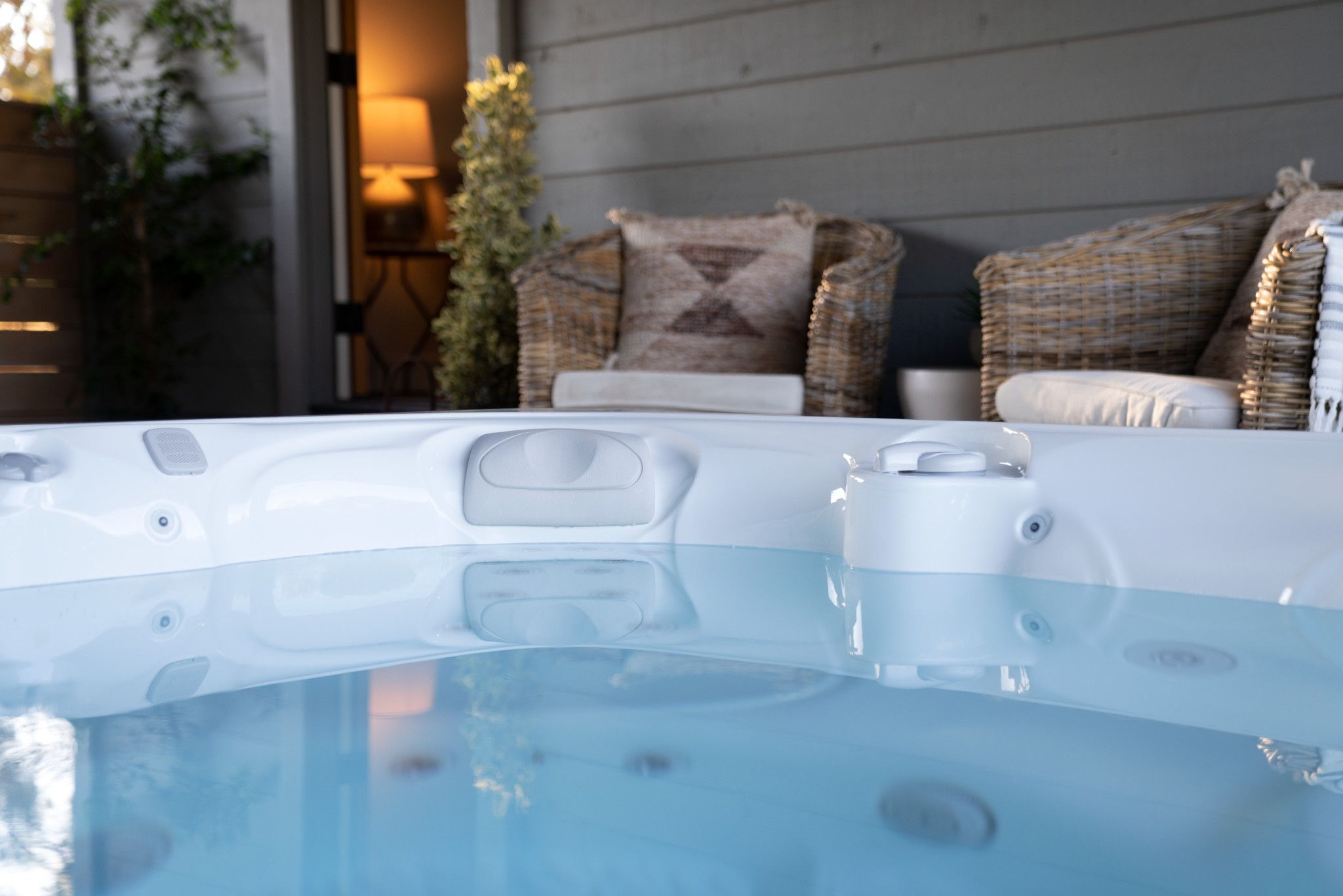 Rustgevende caldera spa met blauwe bubbels en rieten stoelen op de achtergrond