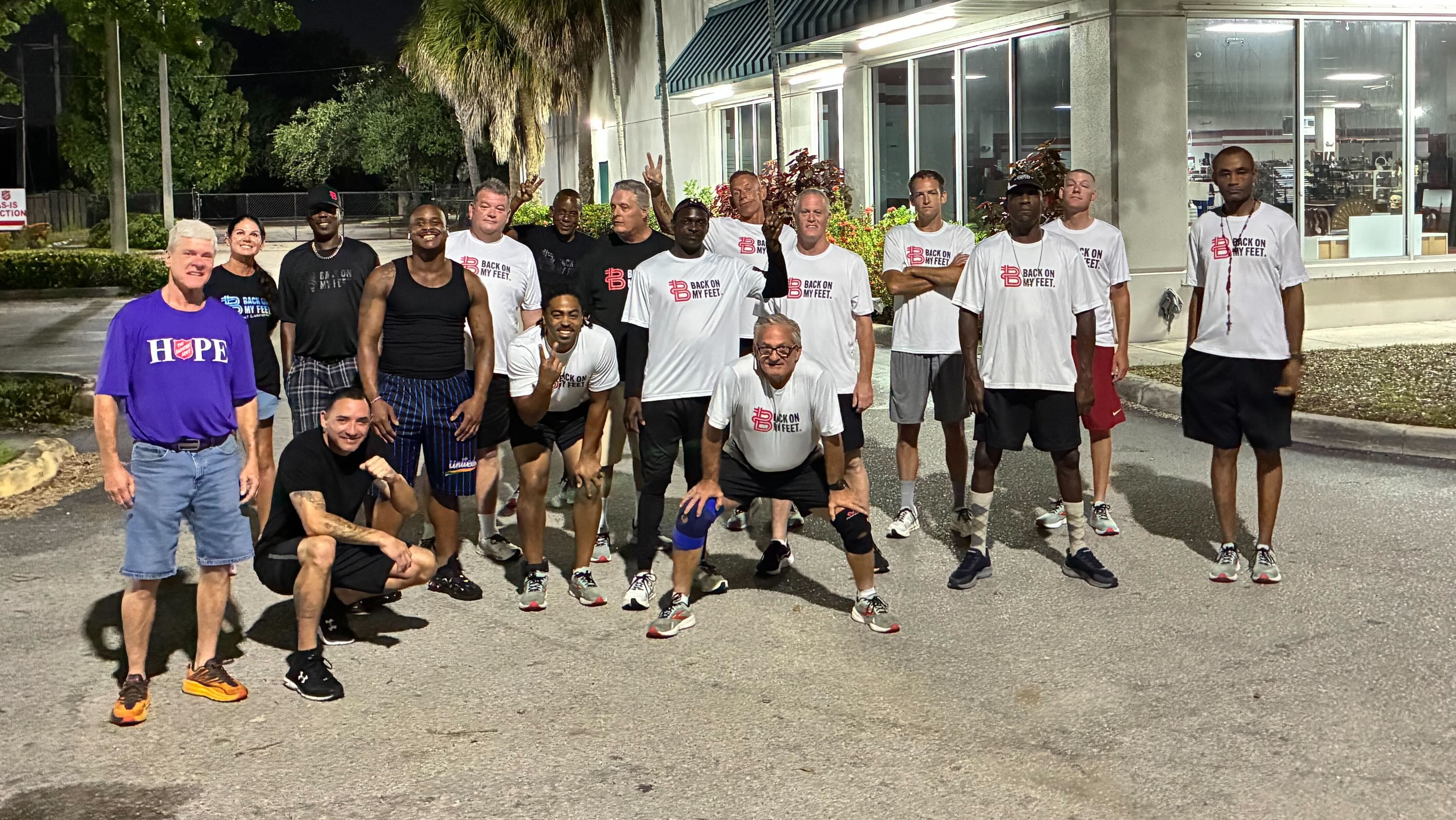 Group of Back on My Feet male members in white shirts posing together outdoors at night