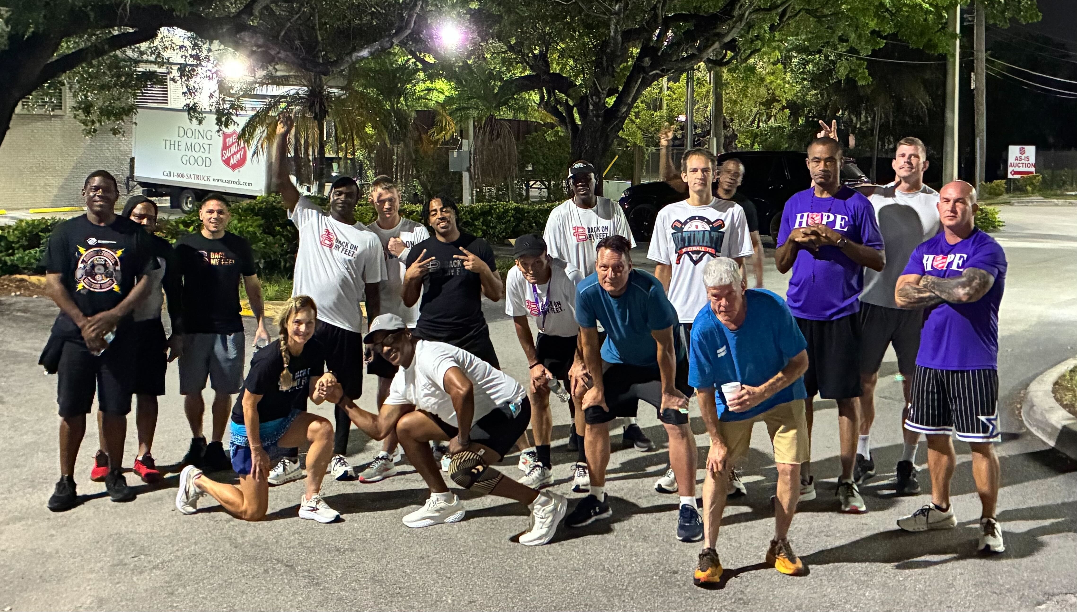 Group of Back on My Feet members wearing Hope shirts posing together outdoors at night