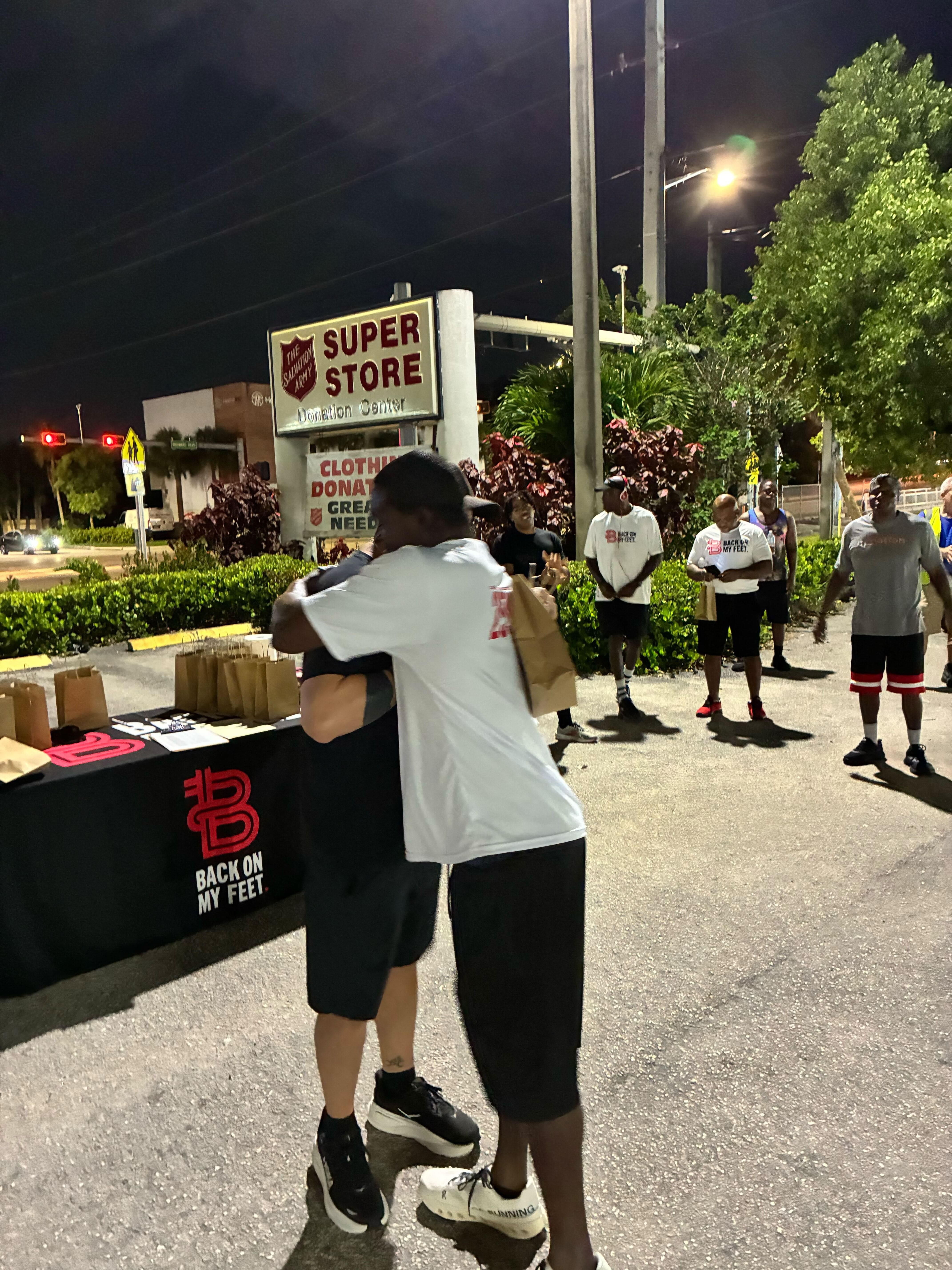 Chuck Matsoff greeting a member at the check-in table during an evening Back on My Feet gathering