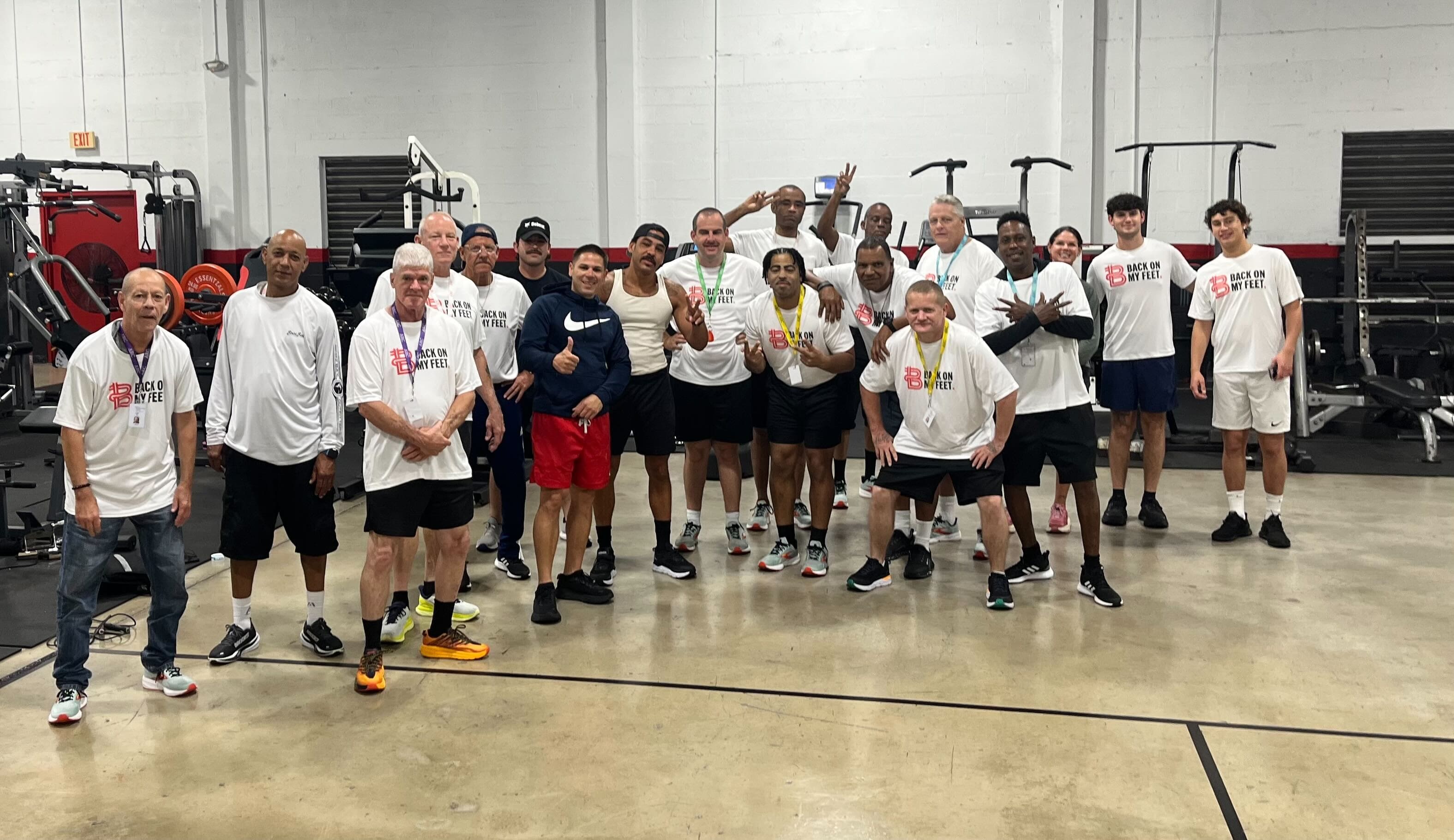 Group of Back on My Feet members posing together indoors in a gym during the day