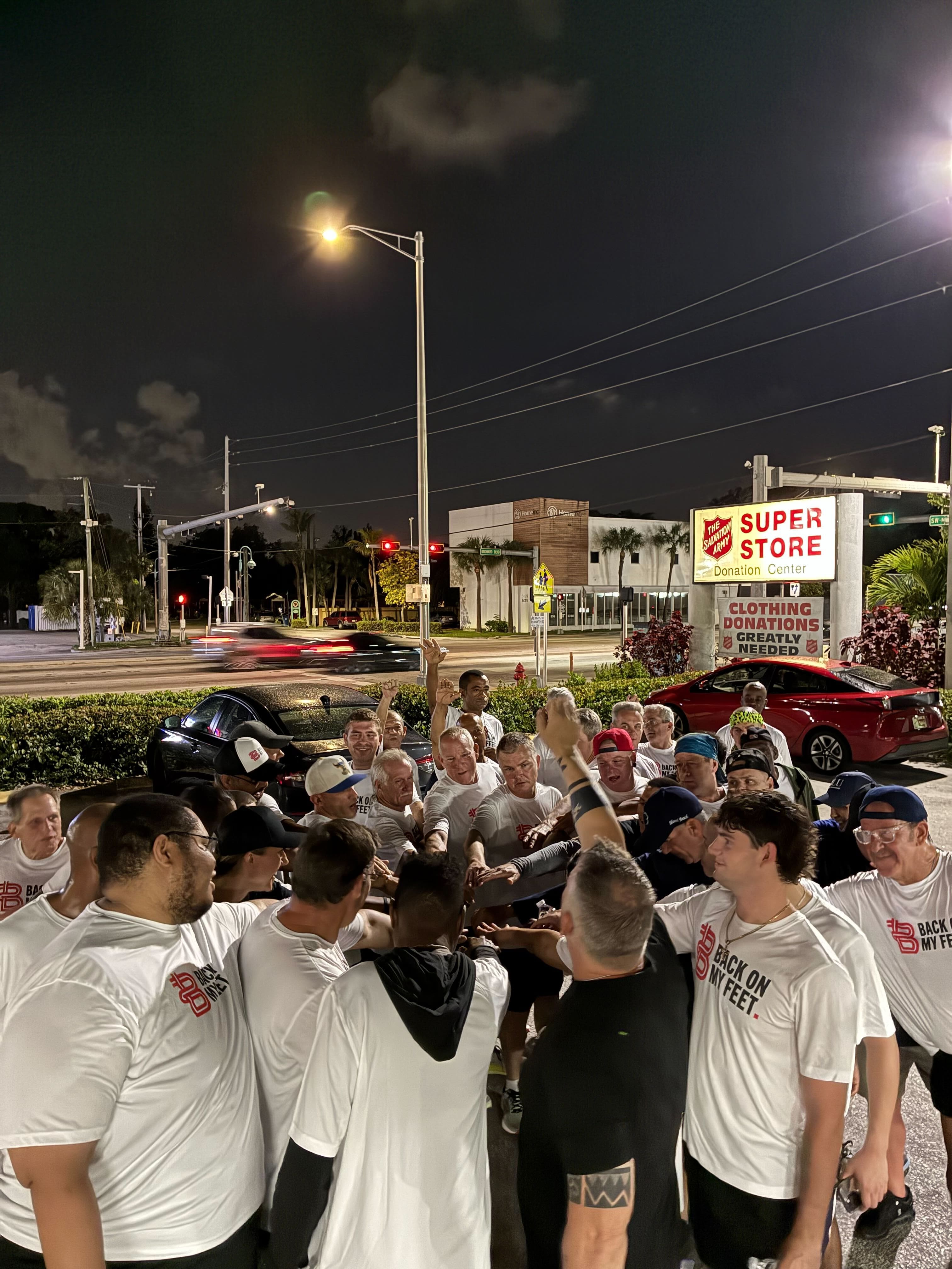 Group of Back on My Feet members gathering at night near the Super Store meeting point before a run