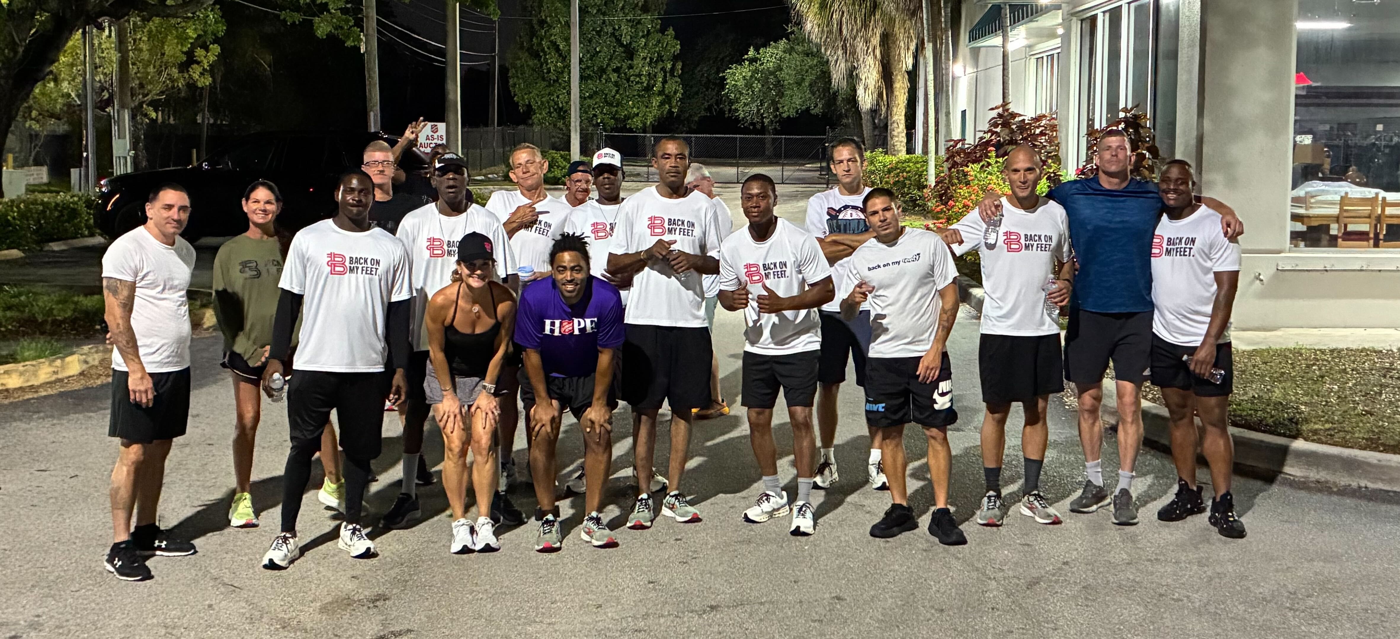 Large group of Back on My Feet members and volunteers posing together outdoors at night