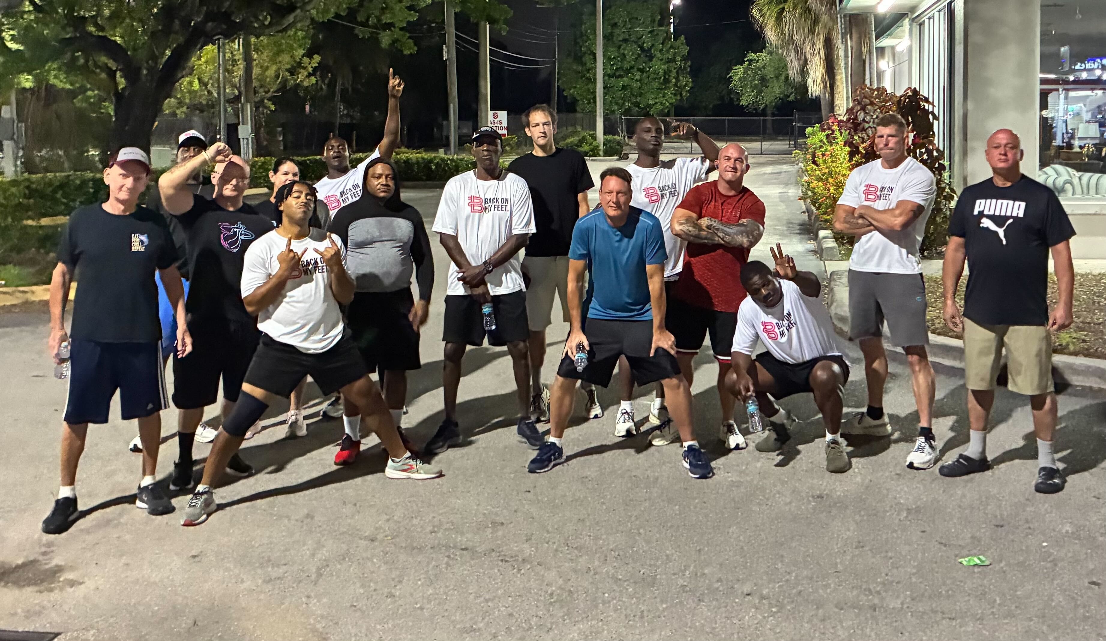 Group of Back on My Feet members posing together outdoors at night after a run