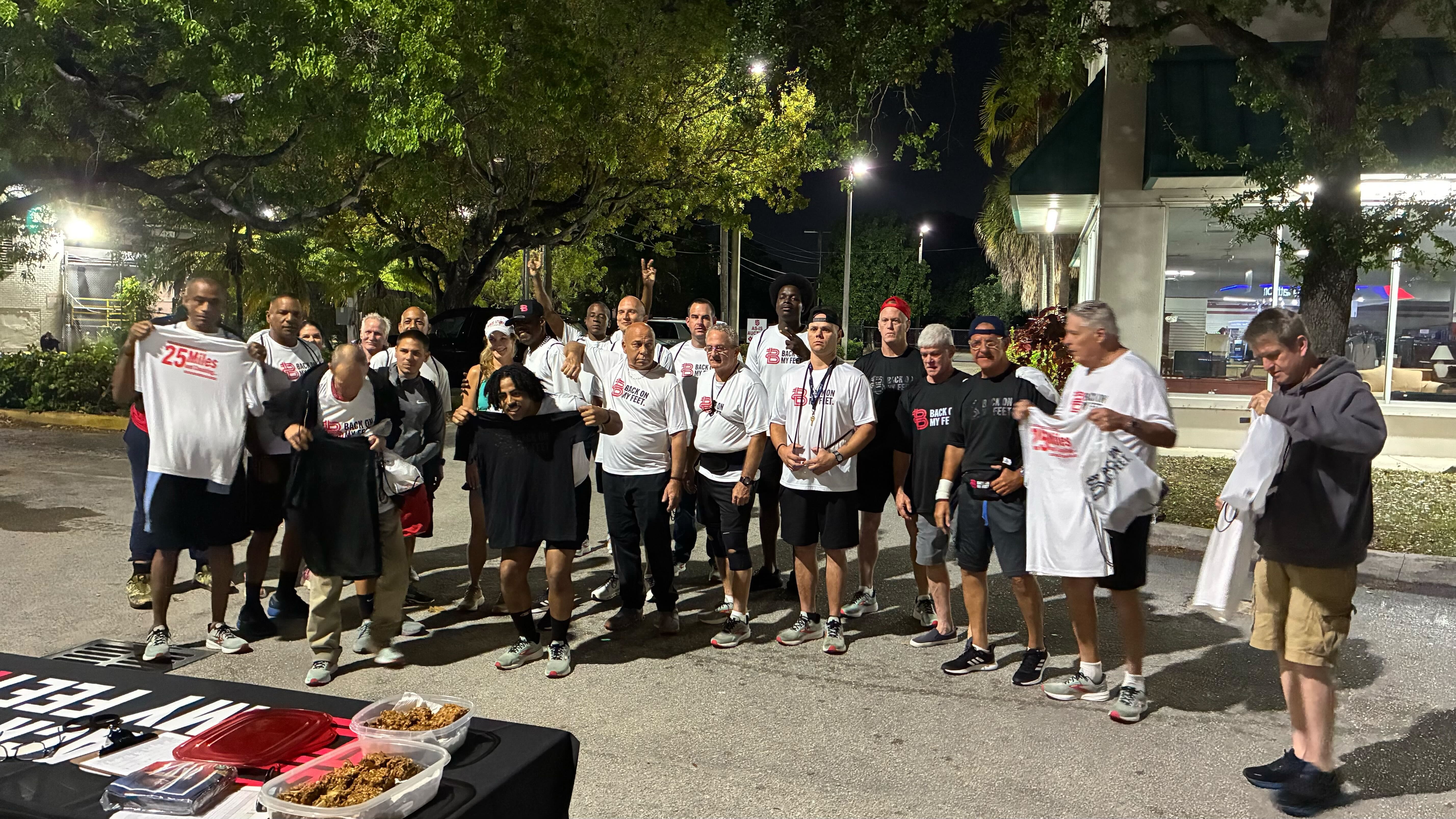 Group of Back on My Feet members gathering outside a lit building before an early morning run