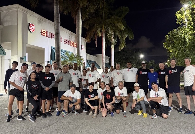Back on My Feet runners posing in a large group outside a store at night