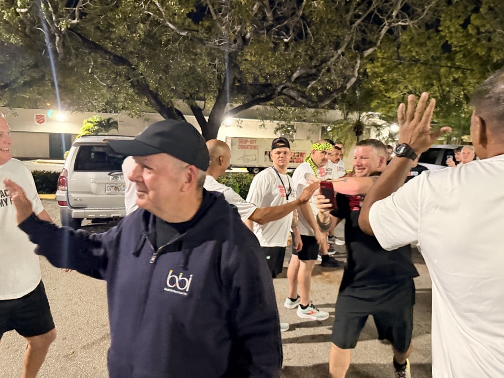Man in a black BBI hoodie high-fiving runners