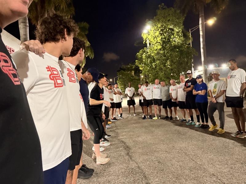 Runners lined up along a sidewalk at night, ready to start