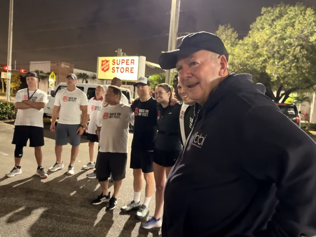 Smiling man in a black cap with runners behind him