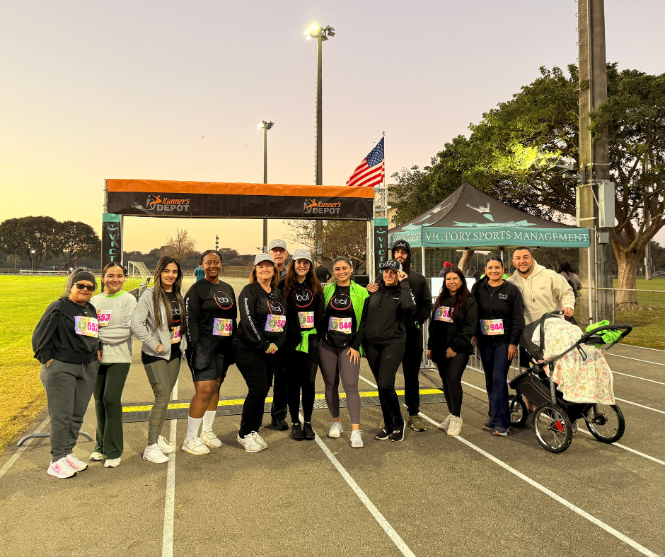 Larger BBI group with a stroller at the finish line arch