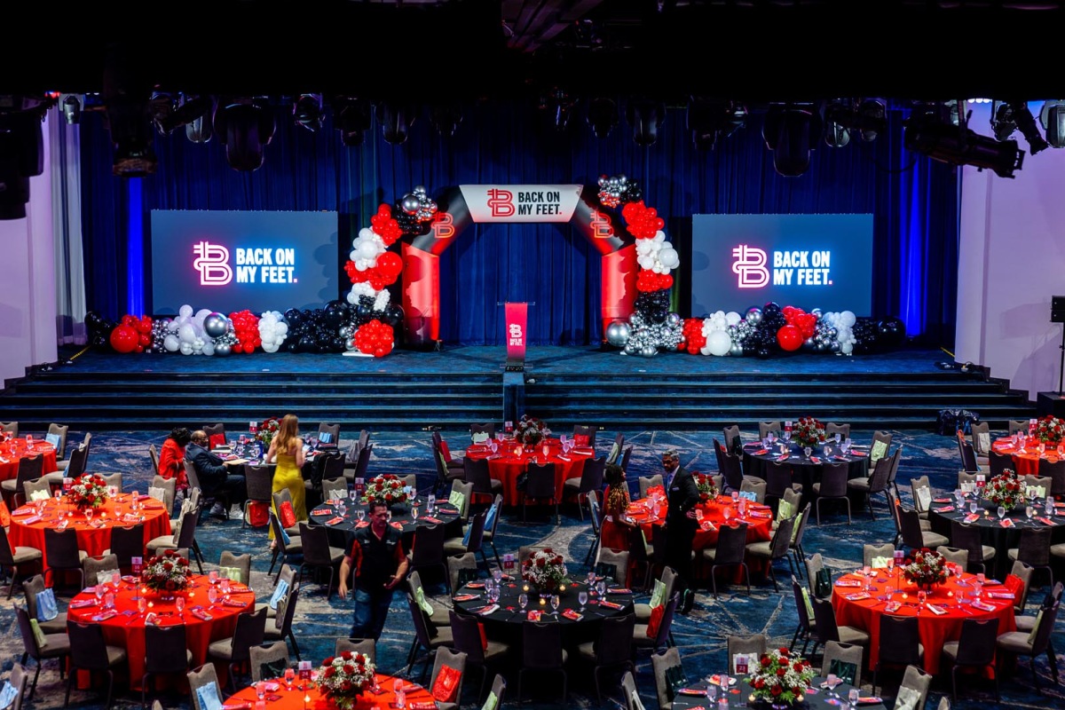 Ballroom set with red-draped tables and a Back on My Feet stage