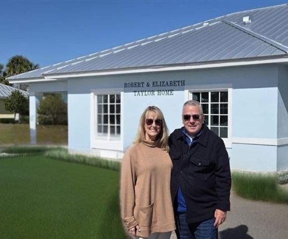 Two people posing by the new home's entrance sign
