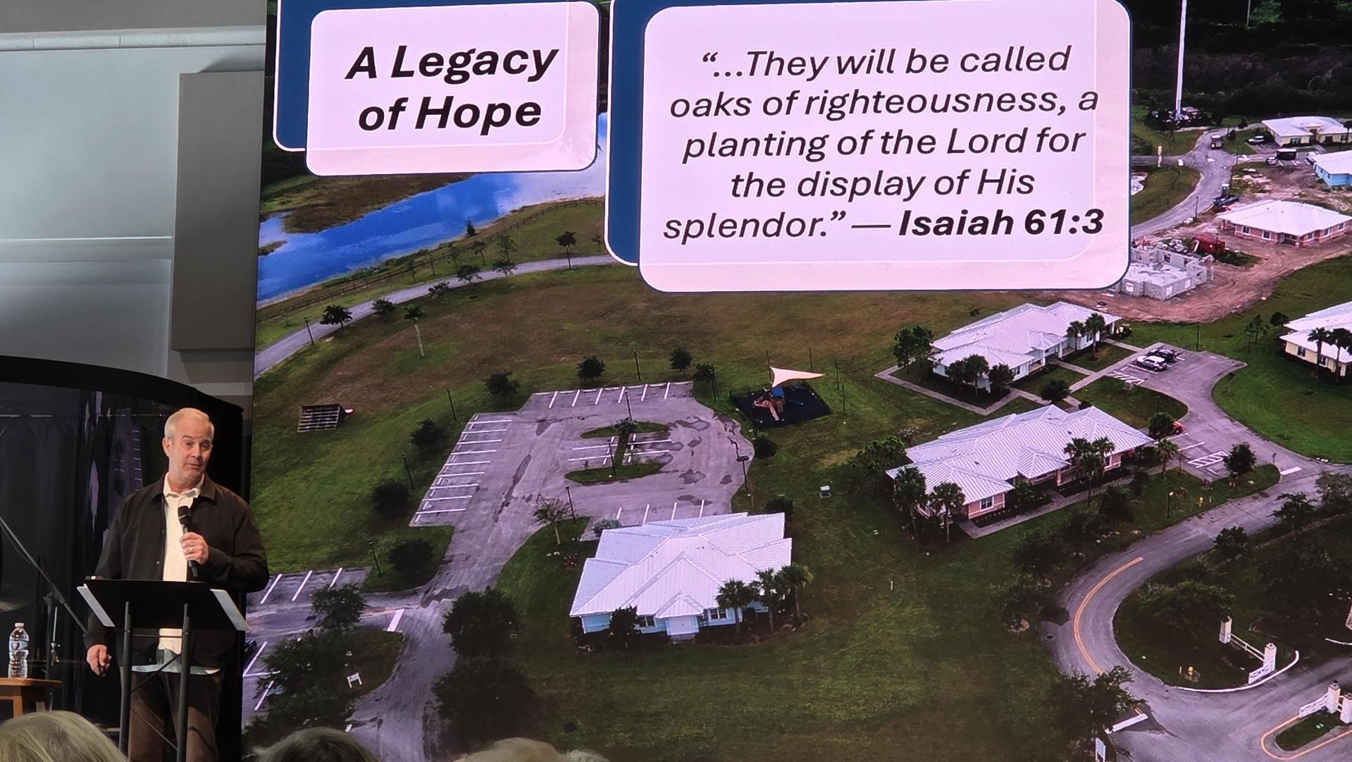 A Legacy of Hope slide with an Isaiah 61:3 verse over an aerial view of the campus