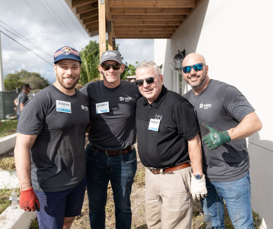 Three volunteers in black shirts posing at the build site