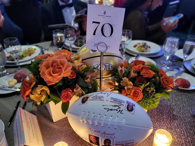 BBI's table at the gala, with a floral centerpiece and a signed football