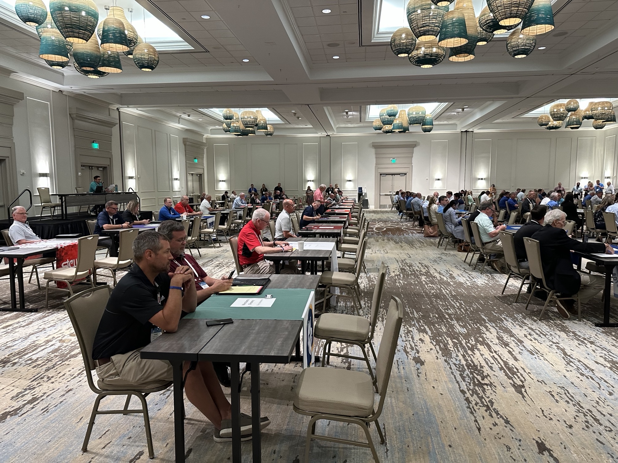 Wide view of a ballroom filled with rows of small tables set up for one-on-one meetings.
