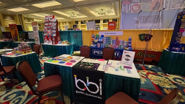 bbi table runner on a green booth table with candy and beads, with Perfetti Van Melle and Reese's displays behind.