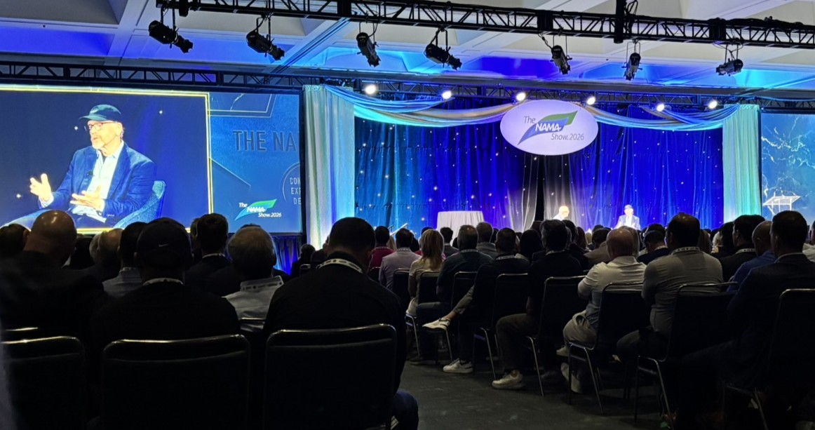 Audience seated in a ballroom facing a stage with a NAMA Show 2026 logo and a speaker on a large screen.