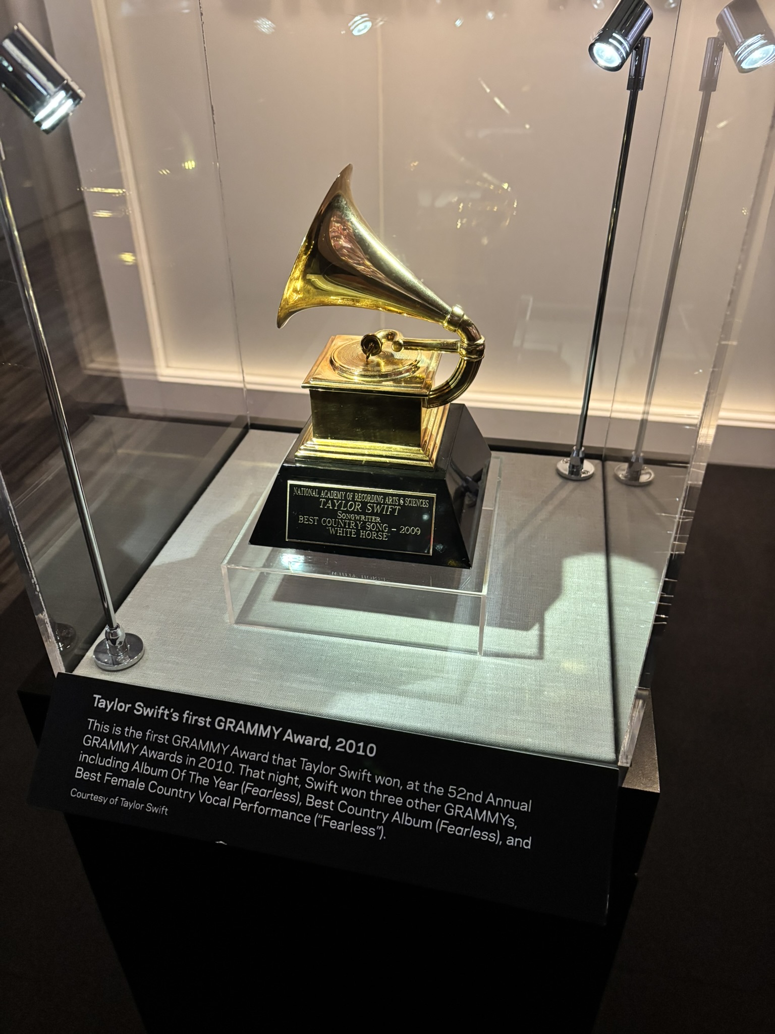 Gold gramophone trophy in a glass case, with a label reading Taylor Swift's first GRAMMY Award, 2010.