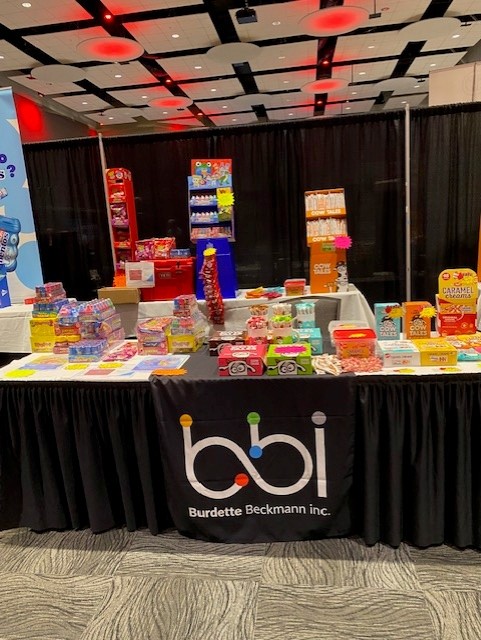bbi table covered in boxed candy and a Caramel Creams display, with red and blue racks behind.