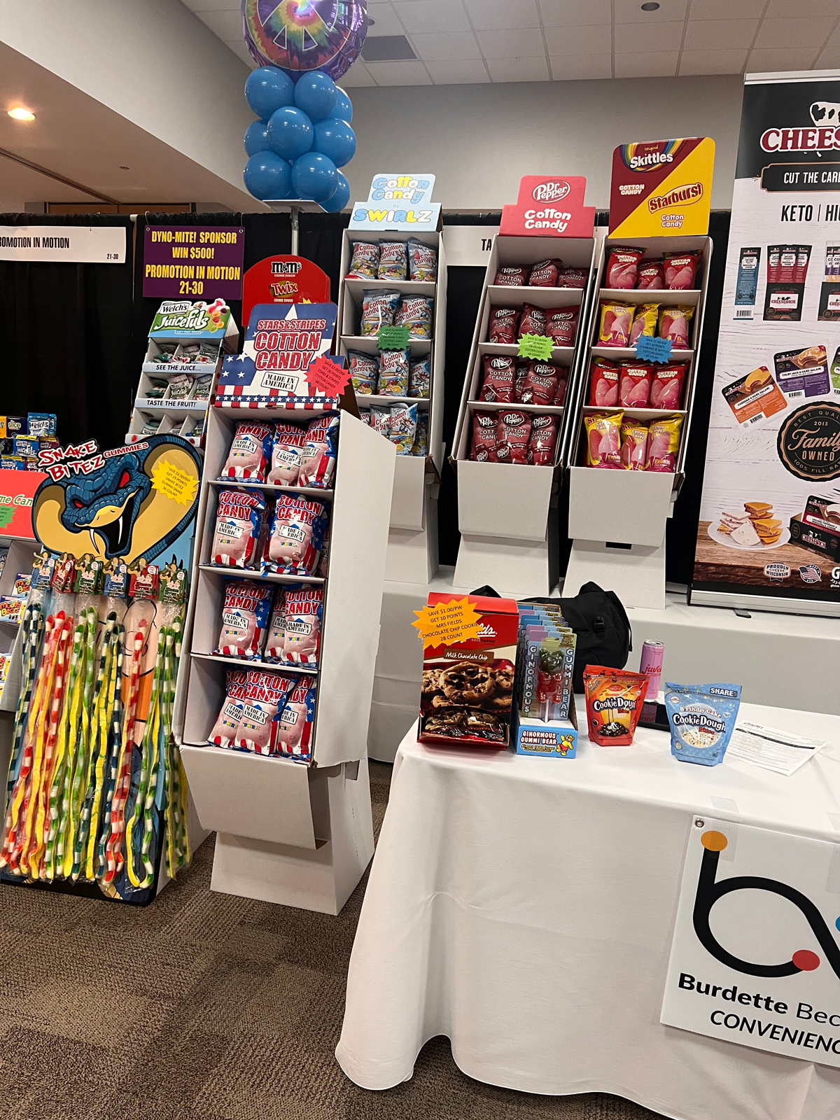 Cotton candy, Dr Pepper and Skittles displays and a Snake Bitez rack beside a table with a bbi Convenience sign.
