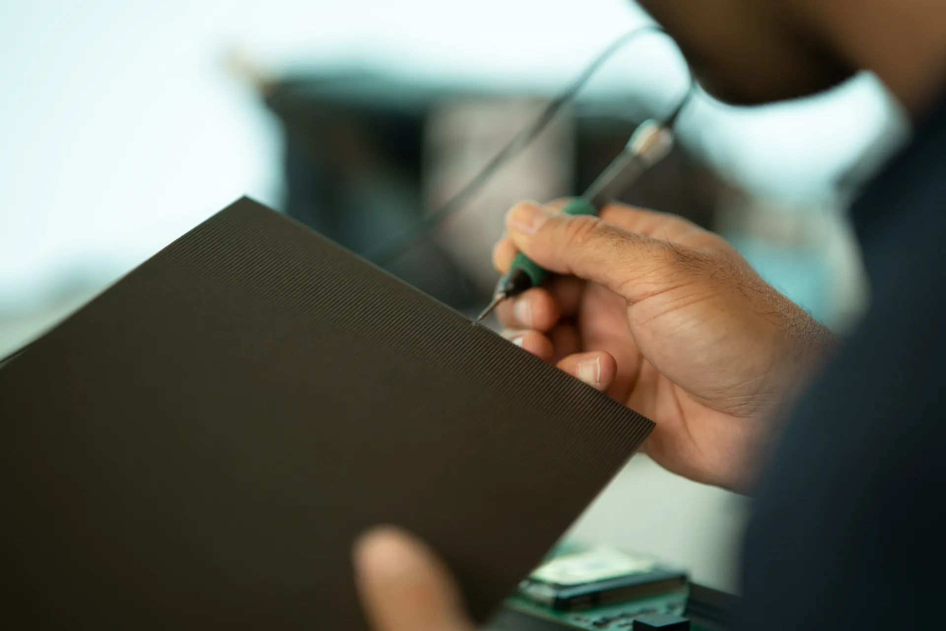 Close-up of a person holding a black led panel using a tool on the pixels.