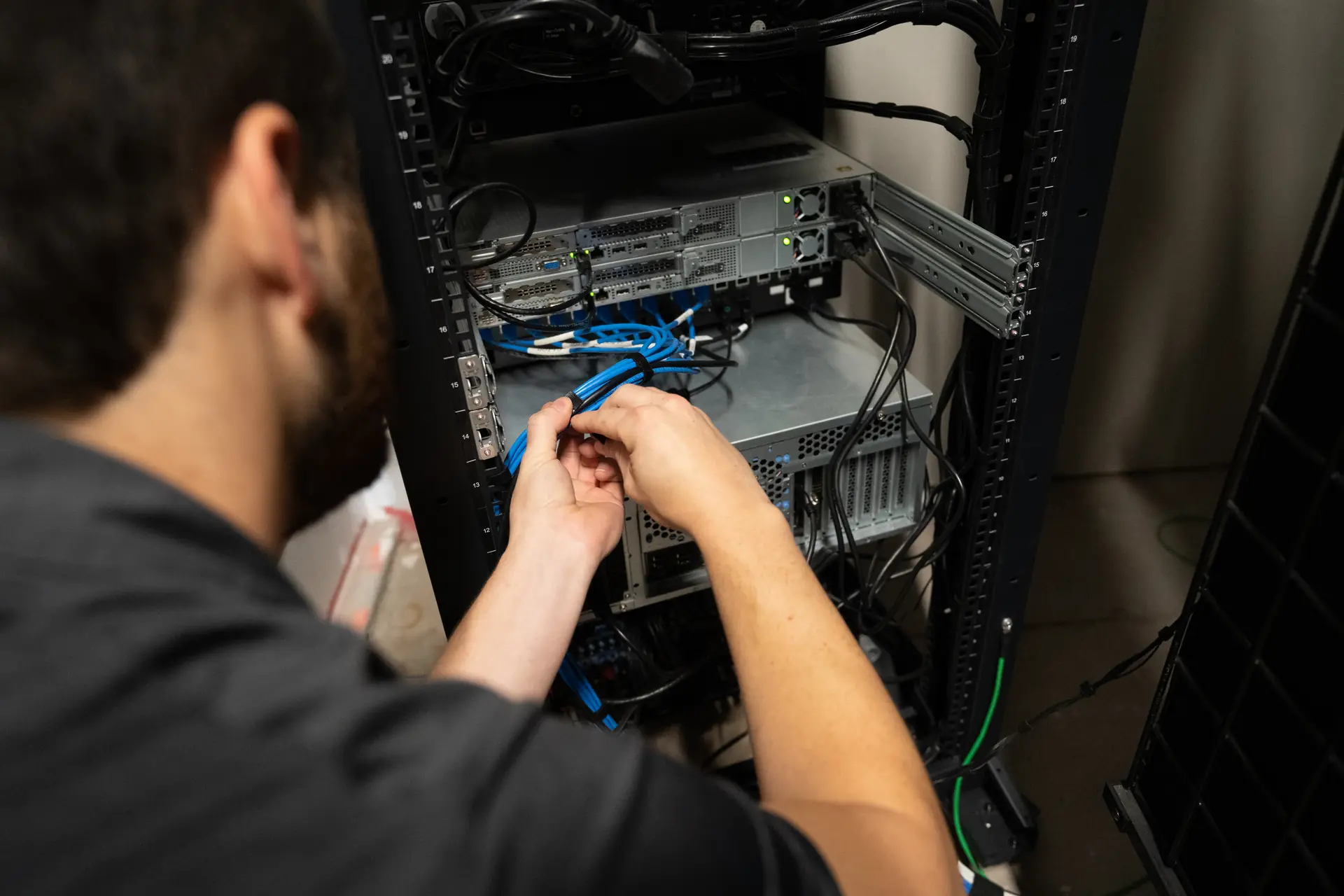 "Technician connecting blue network cables to a server rack in a data center."