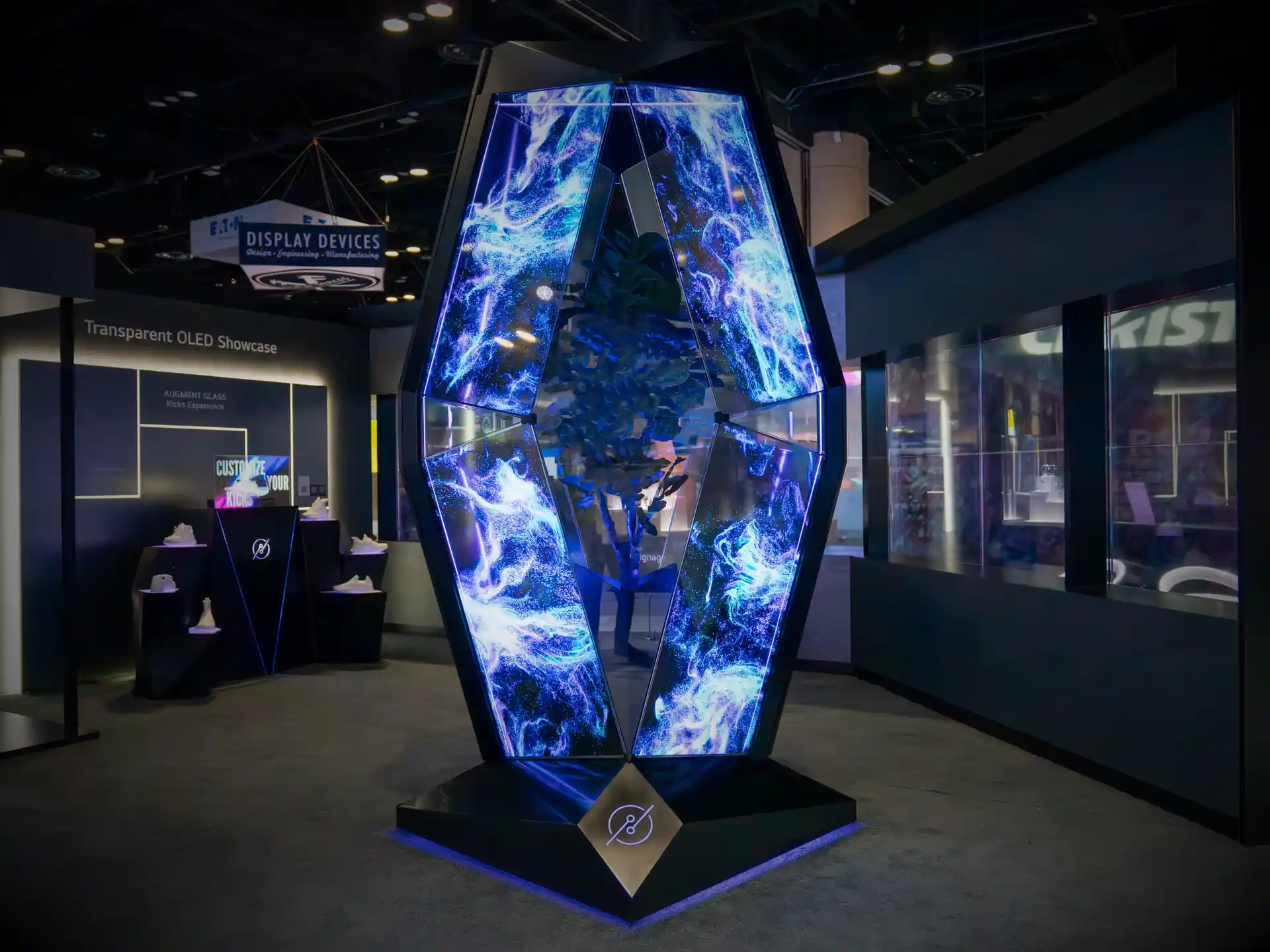 The Vessel’s faceted transparent OLED panels displaying blue and purple abstract visuals on a trade show floor.