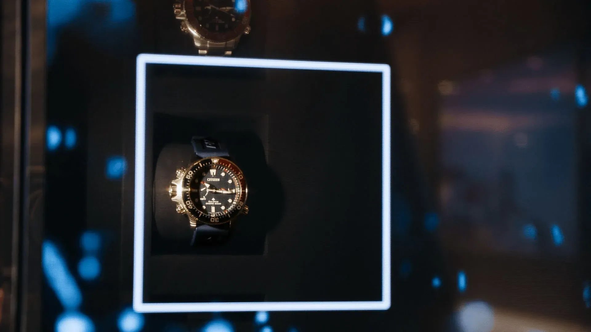 Citizen watch framed by an illuminated square inside an augmented reality display case.