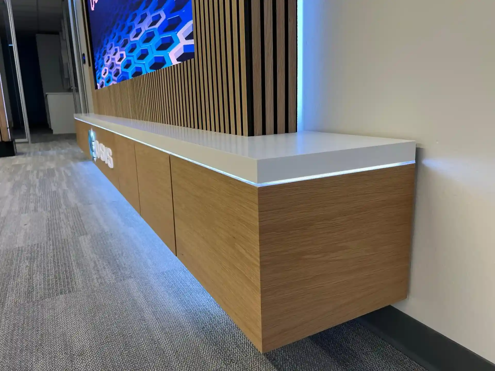 Custom wood cabinetry and white countertop with integrated lighting at the Q-SYS Austin Experience Center.