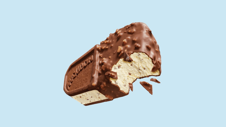 Partially bitten chocolate-coated ice cream bar with vanilla ice cream and chocolate chips inside, against a light blue background.