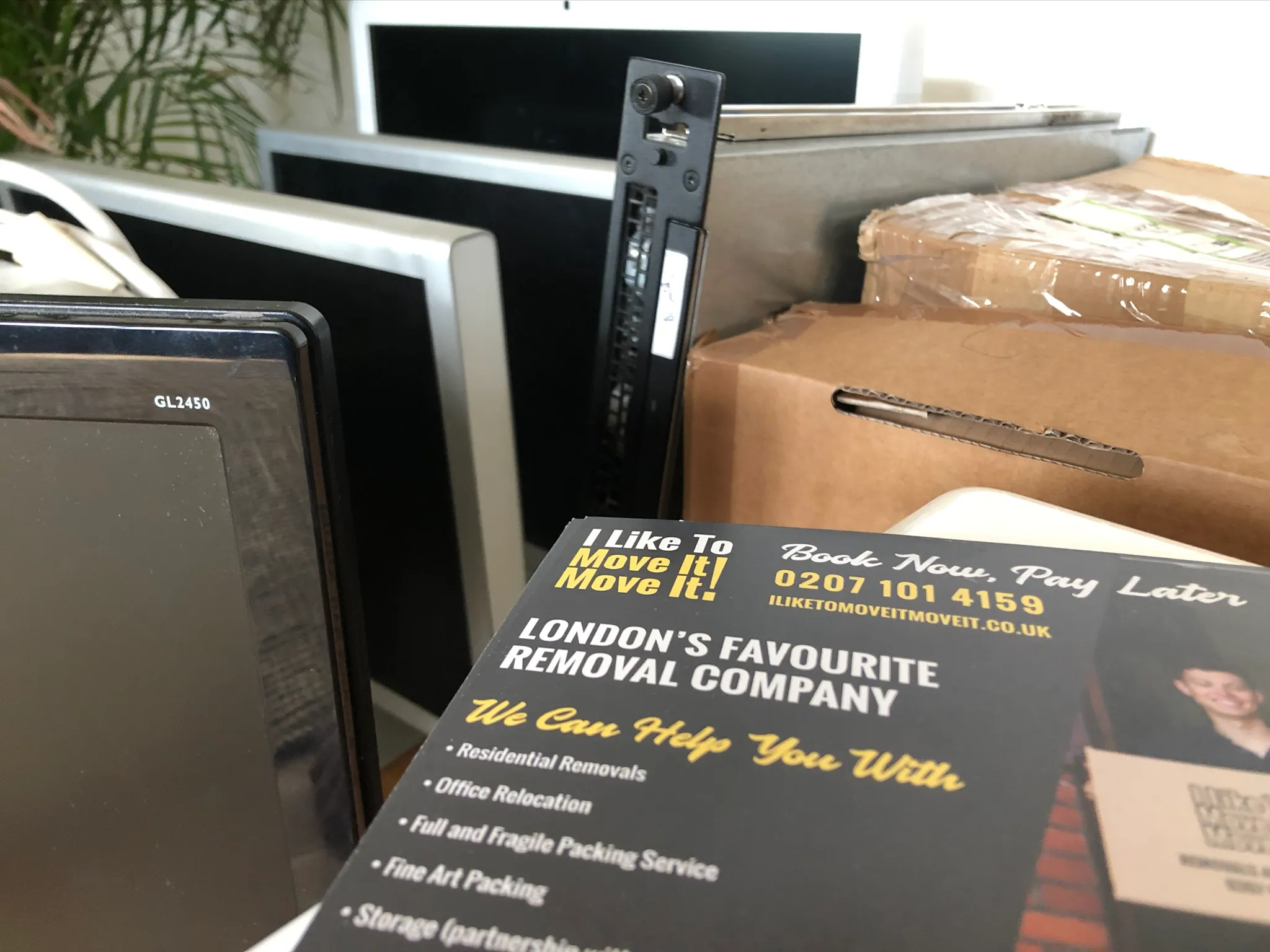 Flyer for 'I Like To Move It! Move It!' London's favourite removal company, surrounded by stacked monitors and cardboard boxes.