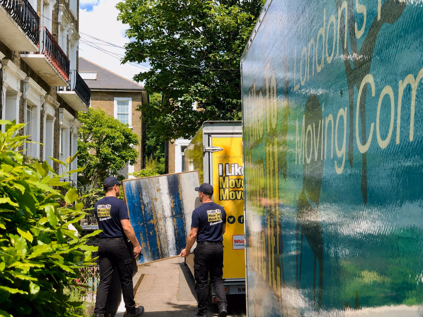 Professional house removals team carrying furniture into a removals van at a London home