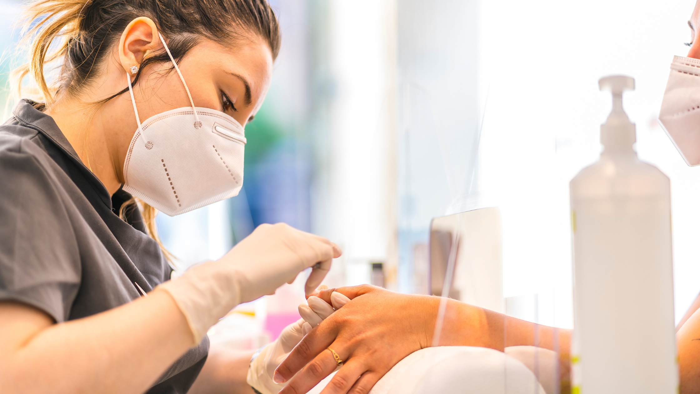 Nail technician's workstation with a clear monomer bottle, brush, and acrylic powder