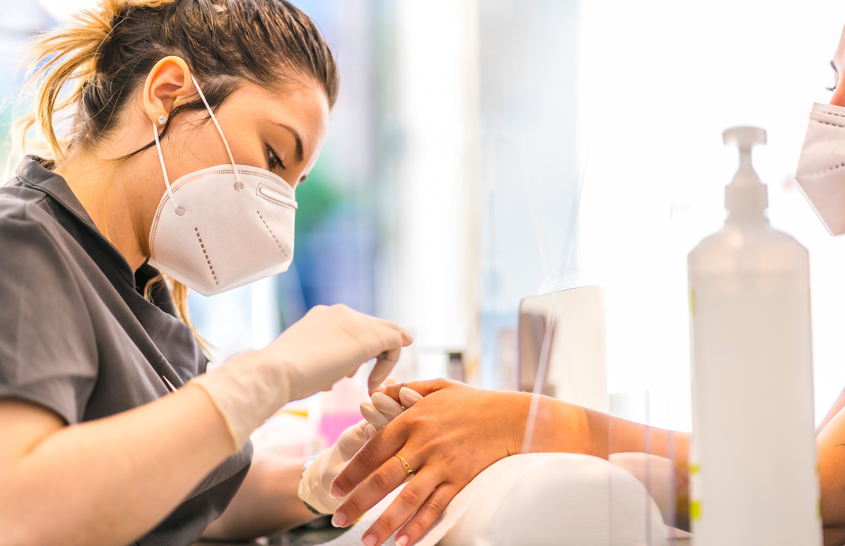 Nail technician's workstation with a clear monomer bottle, brush, and acrylic powder
