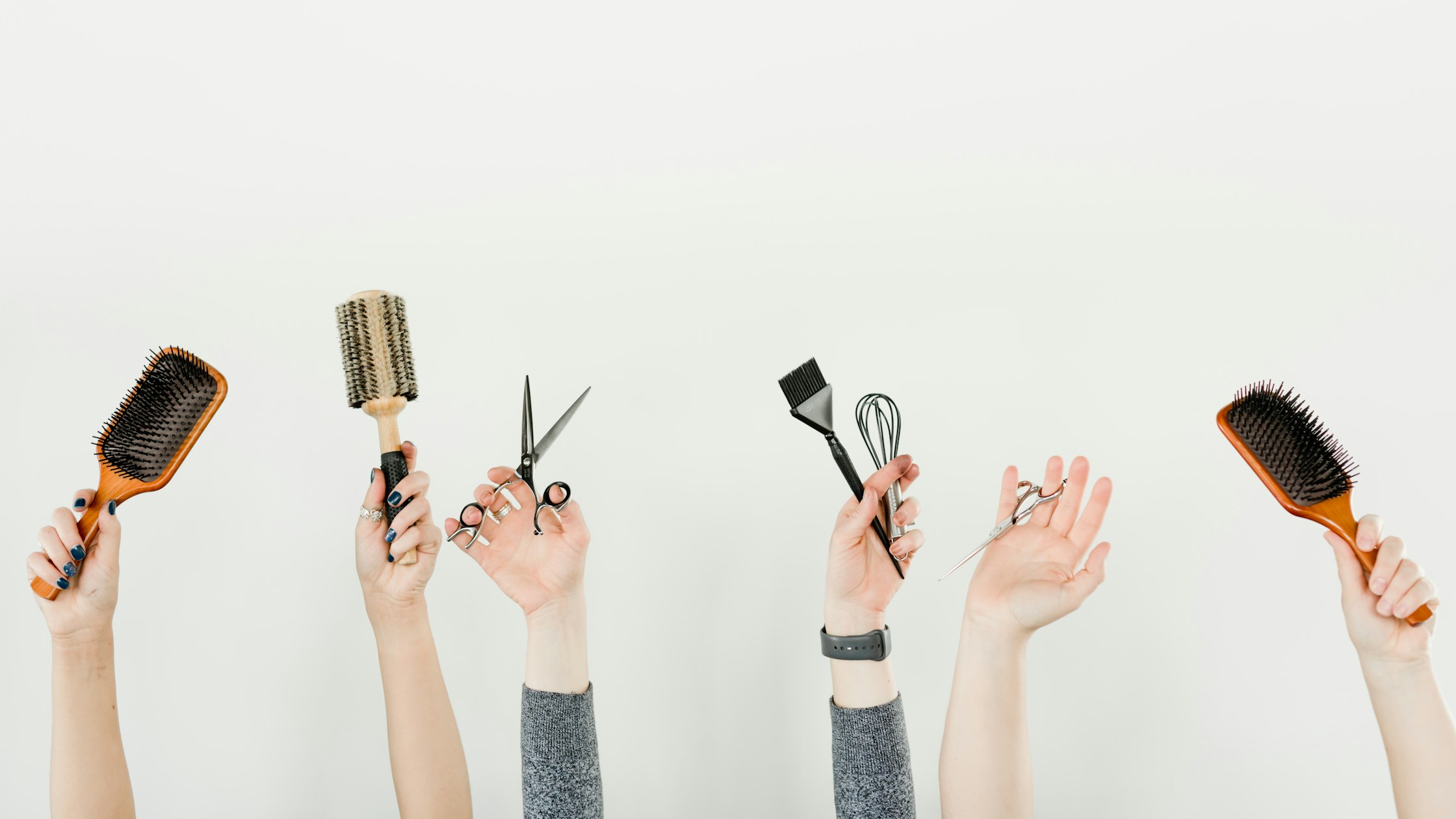 A stylist holding a professional hair brush alongside salon styling tools