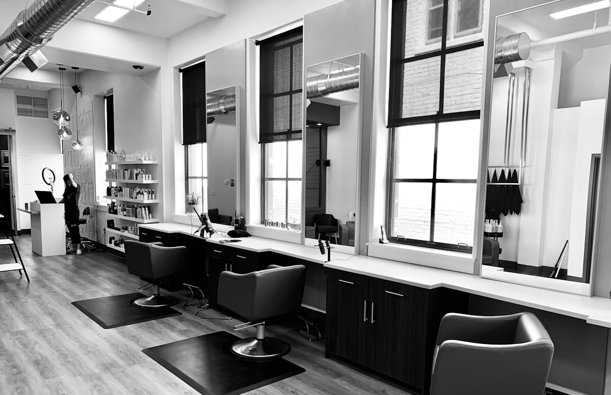 Woman working on a laptop beside salon styling chairs