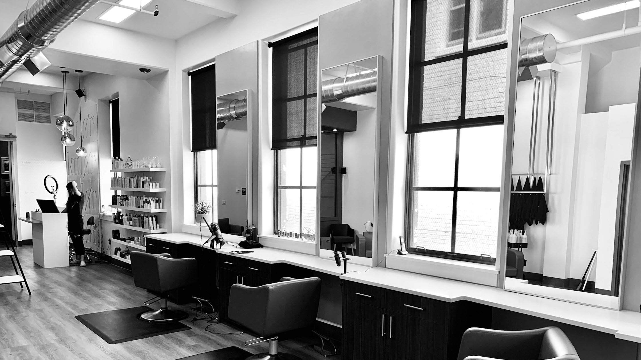 Woman working on a laptop beside salon styling chairs