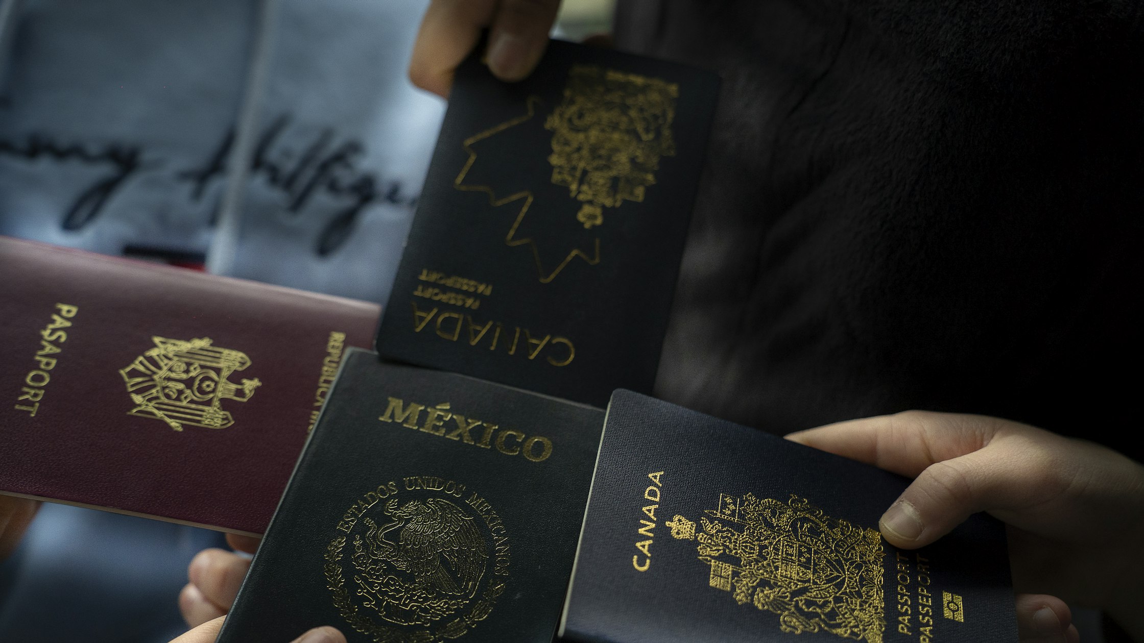 Four people holding passports from different countries, representing non-citizens who qualify for FAFSA at beauty school
