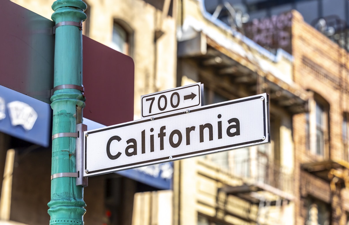 A California street sign with a building in the background