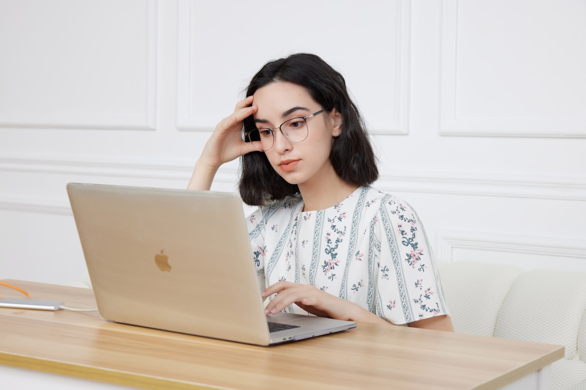 A young woman sitting in front of a laptop comparing federal grant and student loan options for beauty school