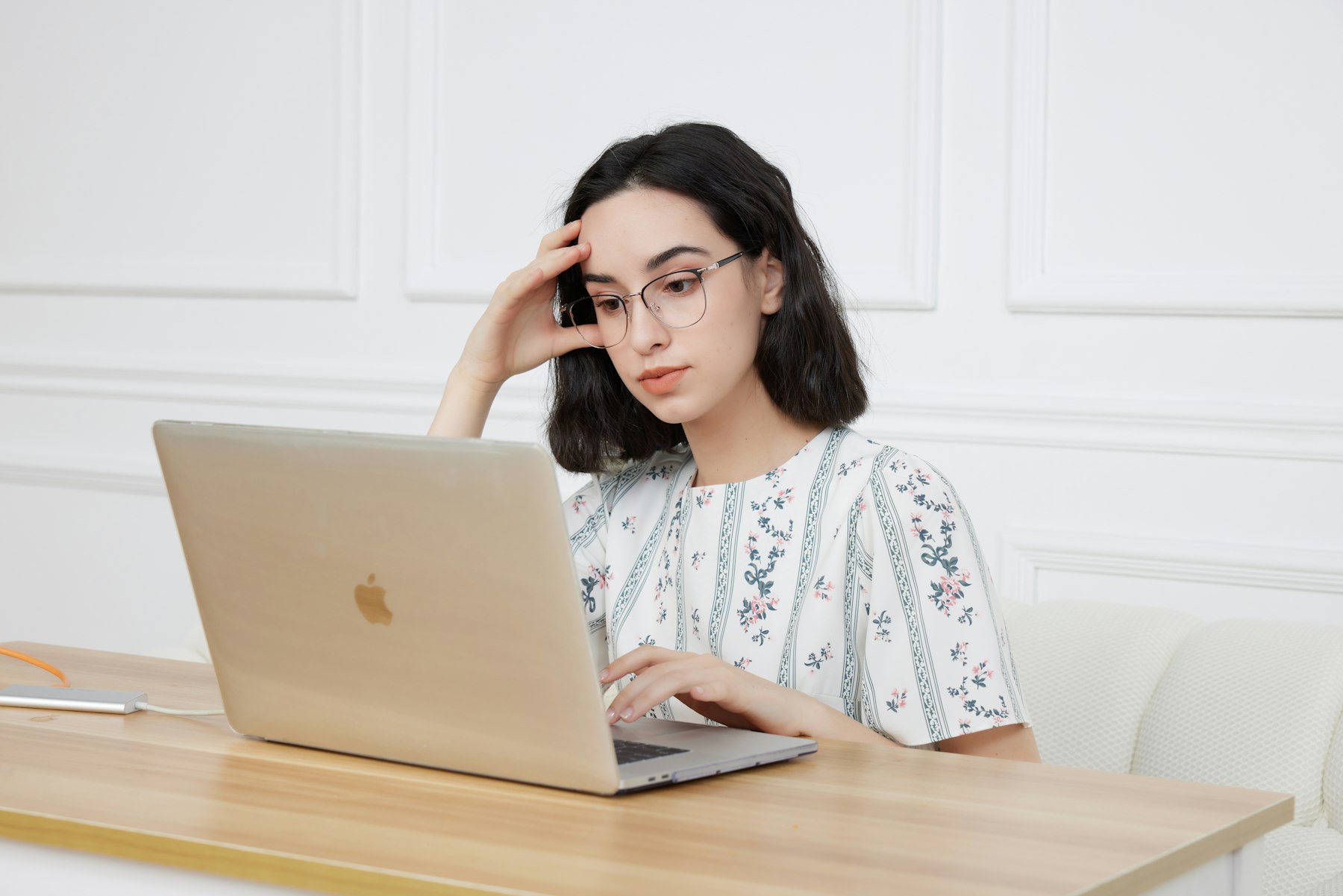 A young woman sitting in front of a laptop comparing federal grant and student loan options for beauty school