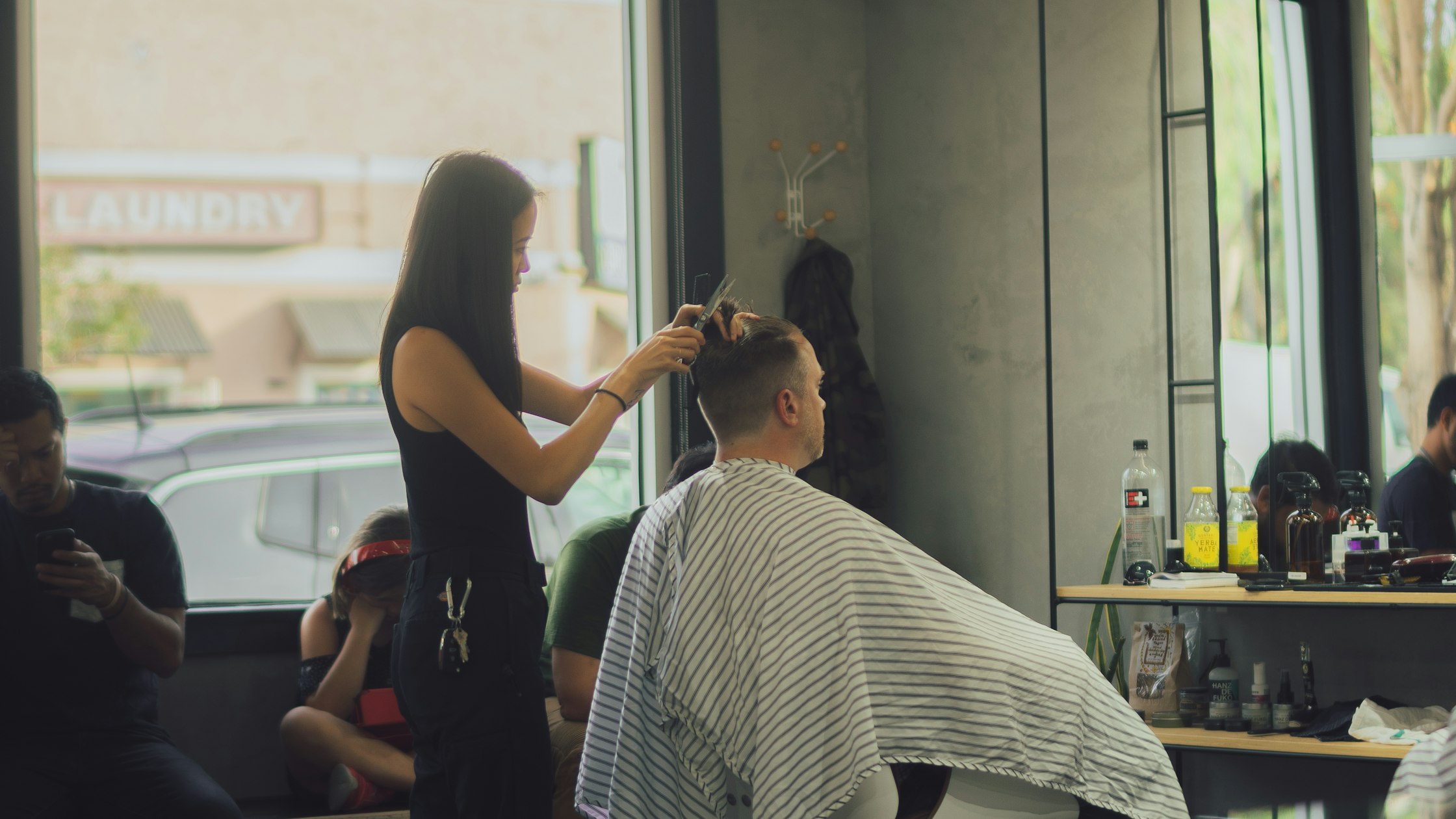 Stylist giving a haircut inside a barber shop — cosmetology vs. barbering license in California