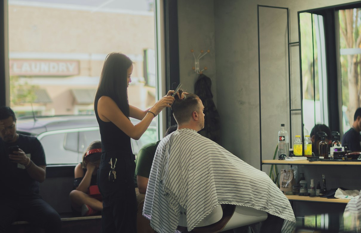 Stylist giving a haircut inside a barber shop — cosmetology vs. barbering license in California