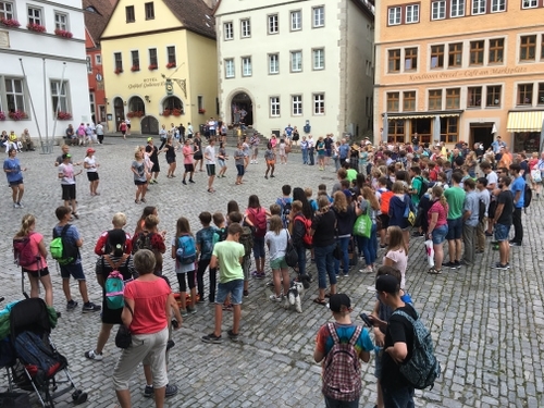 A crowd gathered around a group of Royal Servants doing a street performance.