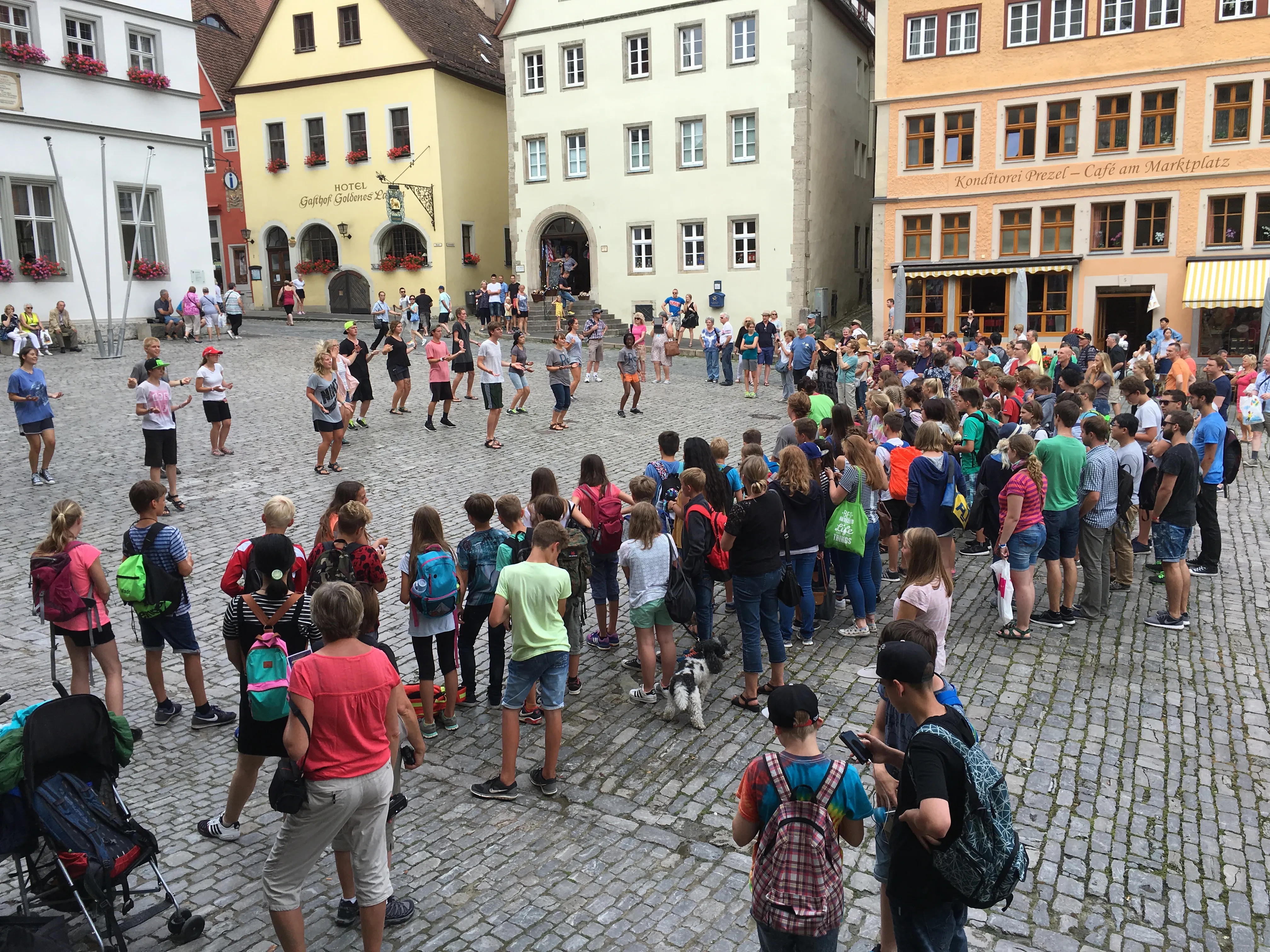 A crowd gathered around a group of Royal Servants doing a street performance.