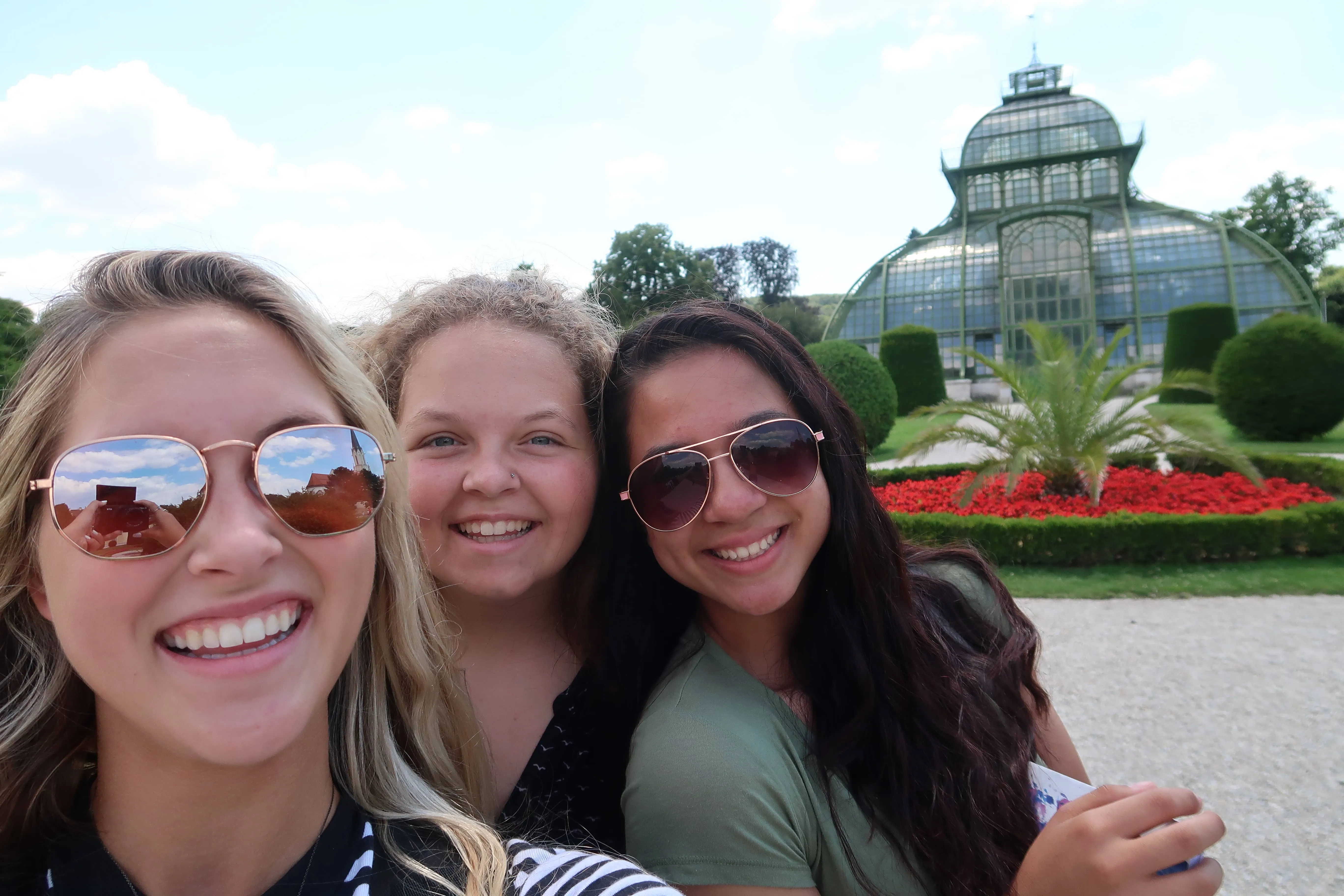 Three Royal Servants in Europe, taking a selfie in front of a glass palace.