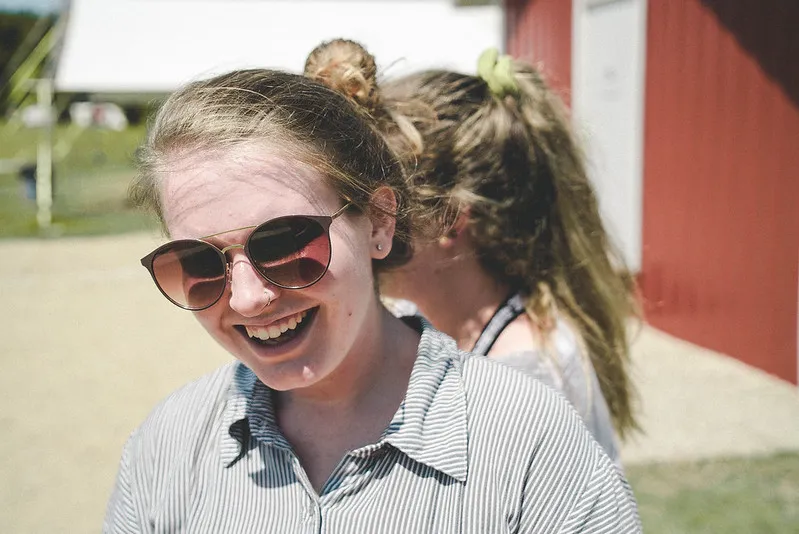 A girl with sunglasses on, grinning.