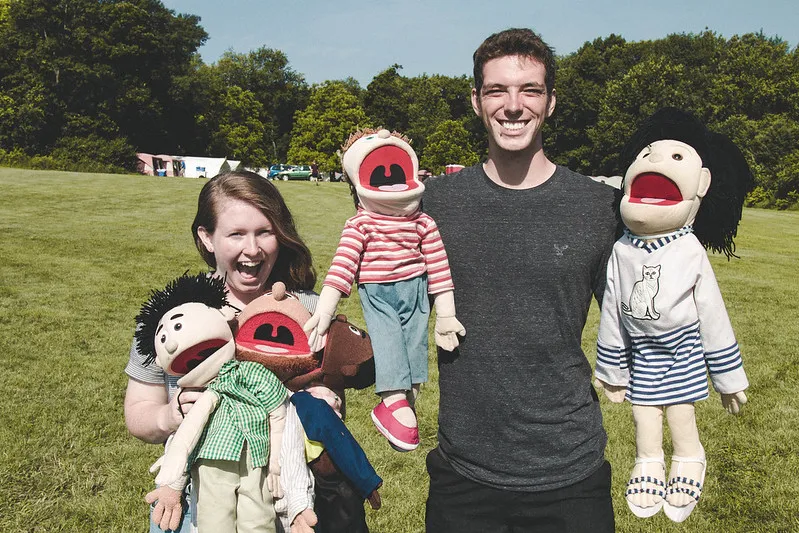 Two volunteers, holding puppets.
